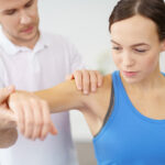 physical therapist testing shoulder movement in patient