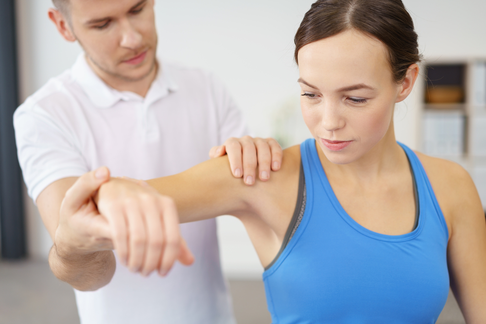 physical therapist testing shoulder movement in patient
