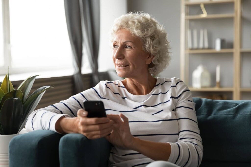 woman holding cell phone sitting on sofa